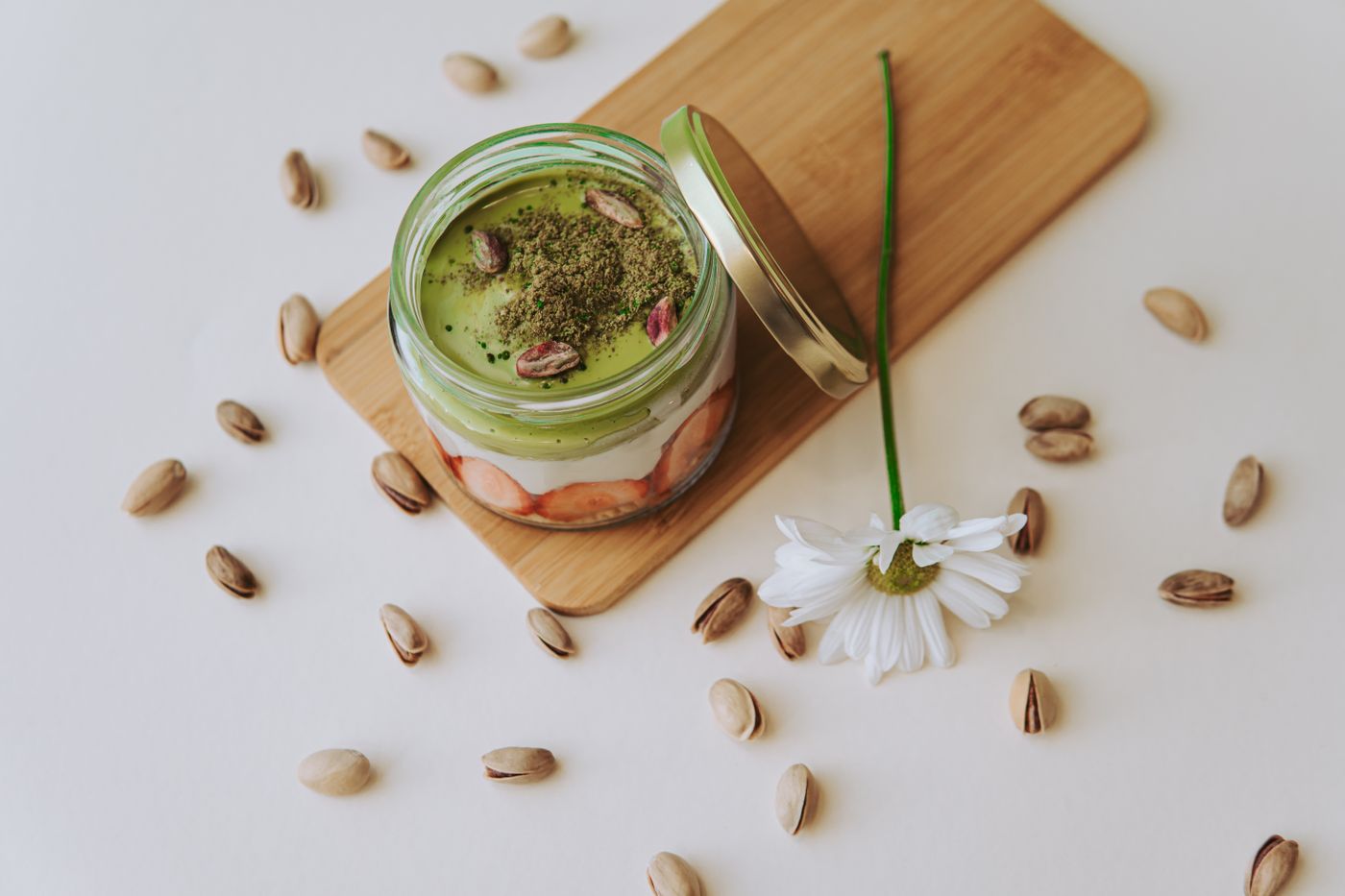Matcha-Erdbeer Glas mit Pistazien und Blume, editorial und modern